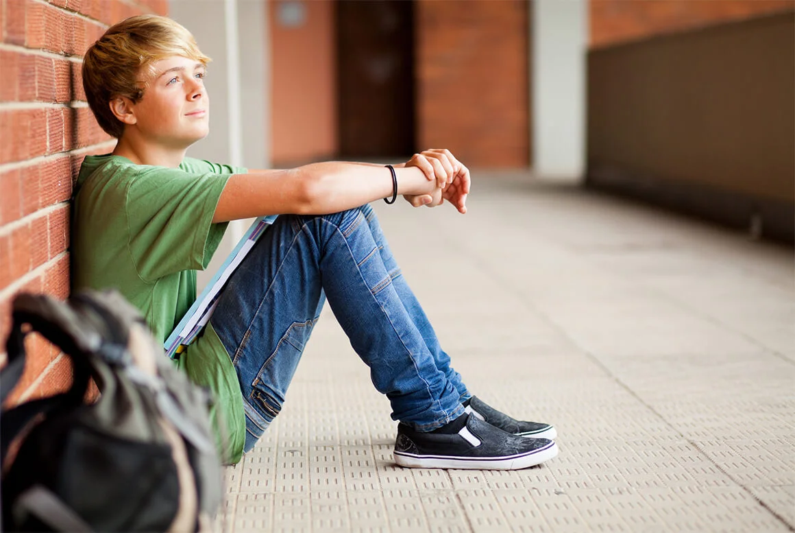 подросток сидит на полу у стены