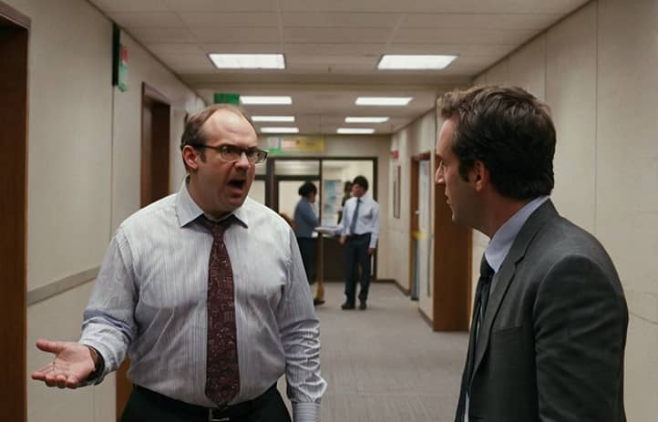 два человека спорят в коридоре офиса